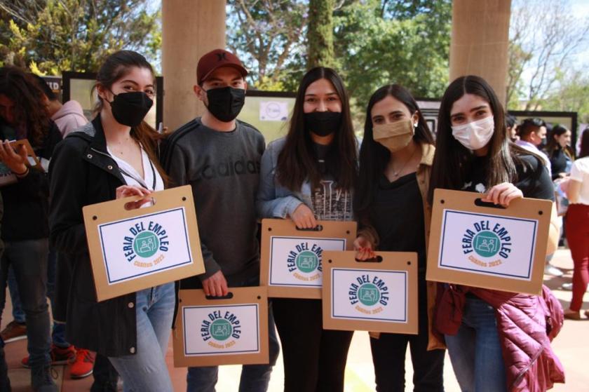 Alumnos sosteniendo folders en los que se lee "Feria del Empleo".