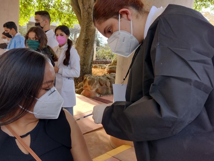 Integrante del programa de vacunación de refuerzo a personal docente aplicando una vacuna.