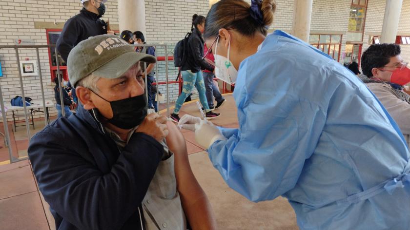 Integrante del programa de vacunación de refuerzo a personal docente aplicando una vacuna.