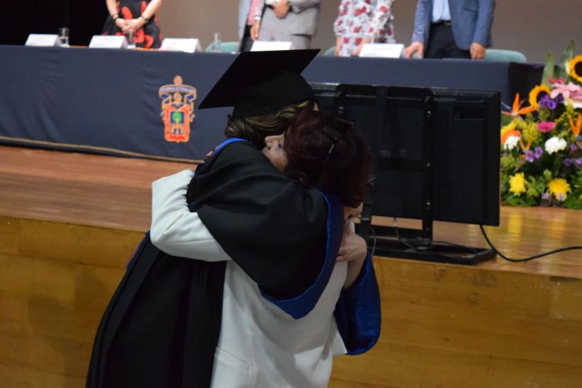 Estudiante abrazando a otra persona en Ceremonia de Acto académico.