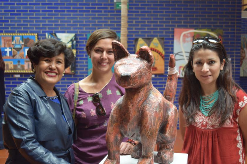 Tres mujeres viendo a la cámara, frente a ellas una obra.