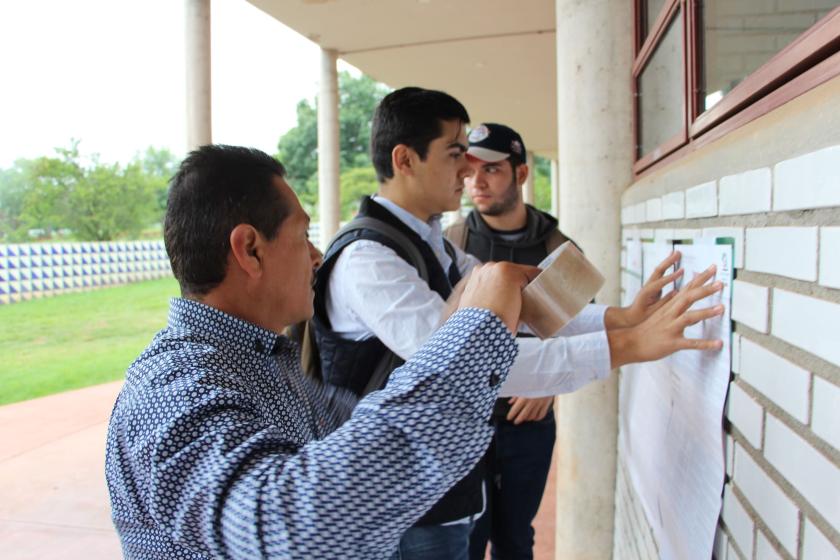 Personas pegando la convocatoria para elegir al próximo Consejo General Universitario.