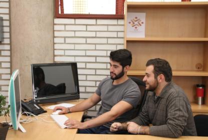 Dos muchachos en el ciio sentados frente a una computadora