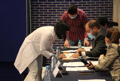 Estudiante firmando frente a autoridades.