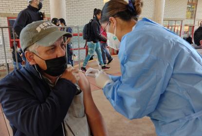 Integrante del programa de vacunación de refuerzo a personal docente aplicando una vacuna.